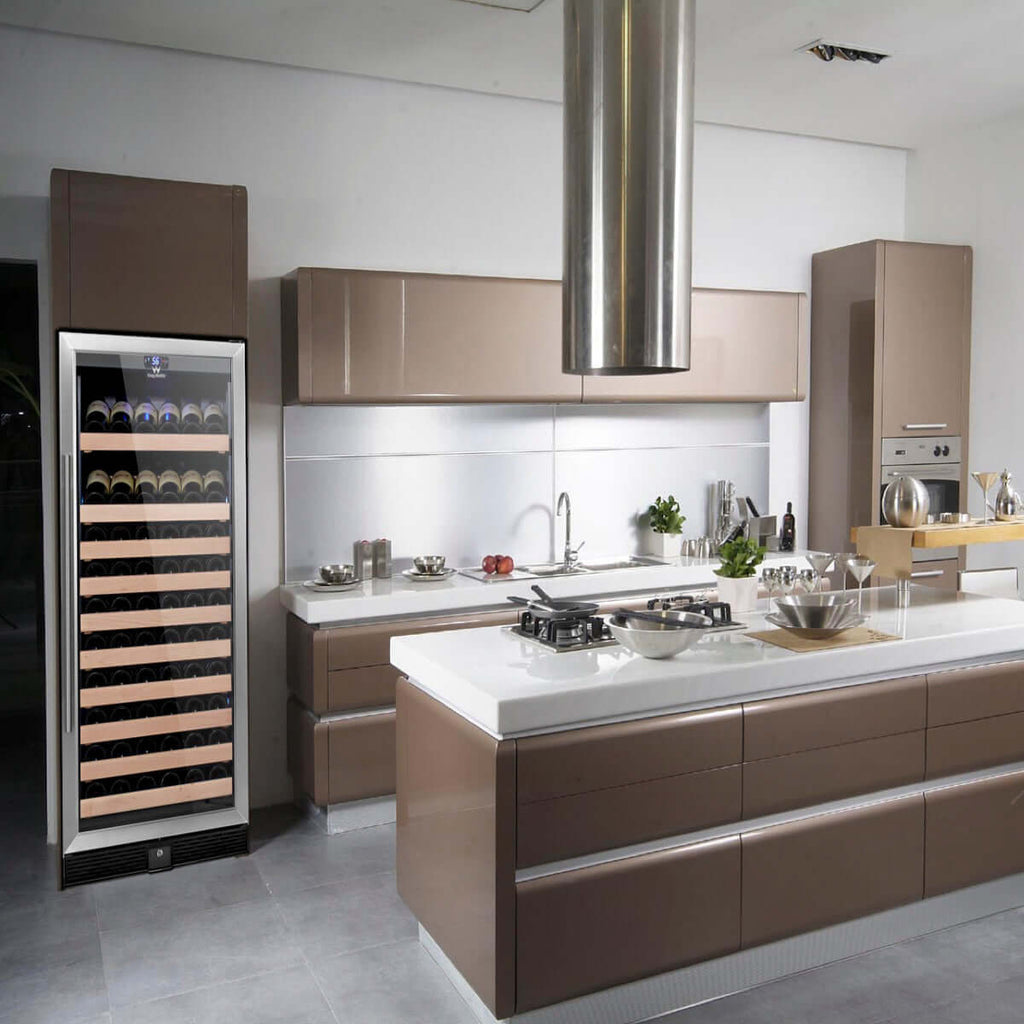 A kitchen with a large island, refrigerator, and wine rack with wine bottles.