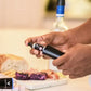 A person holding a black Coravin Pure™ Argon Capsule for wine preservation.