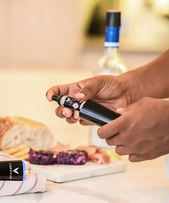 A person holding a black Coravin Pure™ Argon Capsule for wine preservation.