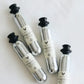A group of silver bottles with black caps, including a close-up of a bottle and a tube. These Coravin Pure™ Sparkling CO2 Capsules preserve the taste and effervescence of sparkling wine for up to 4 weeks. Compatible with the Coravin Sparkling™ System.