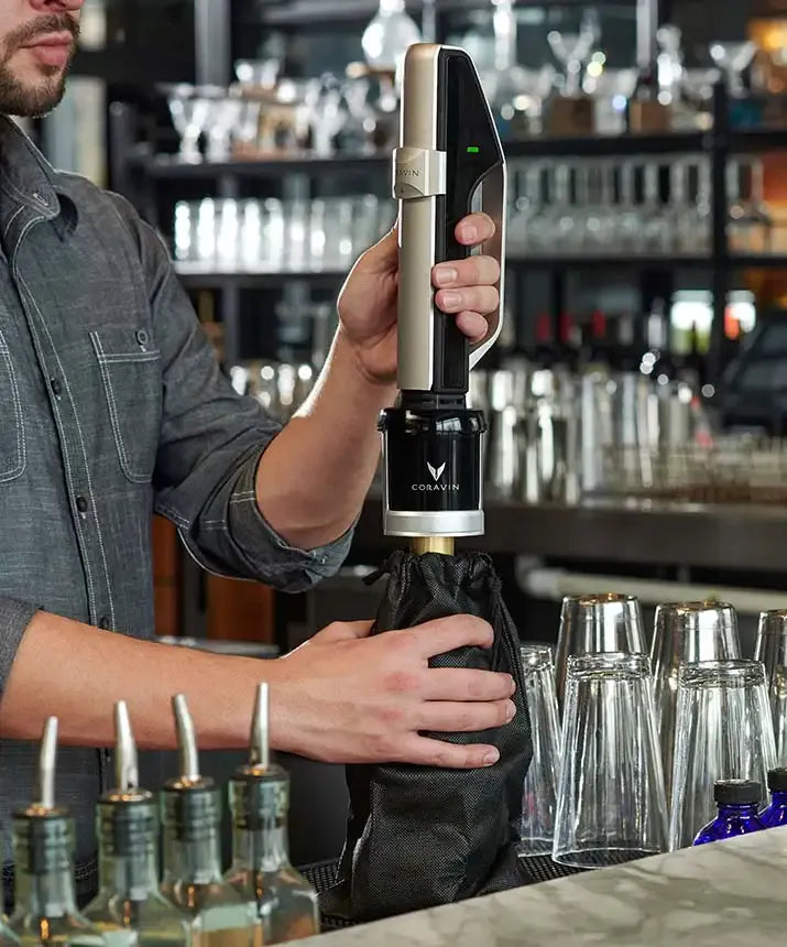 A man holding a black and silver Coravin Sparkling Wine Preservation System.