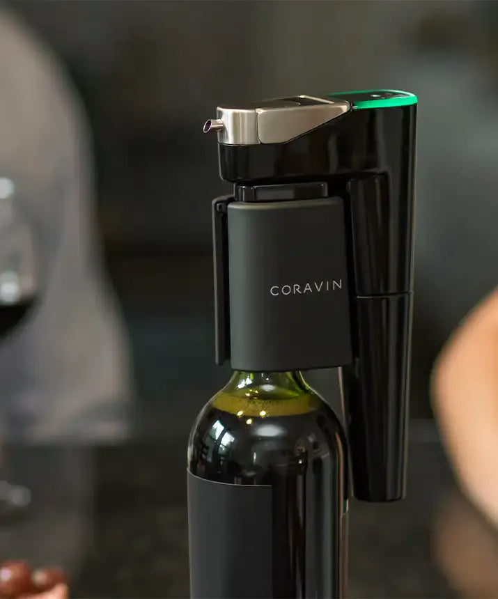 Coravin Timeless Eleven Wine Preservation System: A bottle of wine with a corkscrew, connected to the Coravin Moments App for custom pour speeds and capsule replacement reminders.
