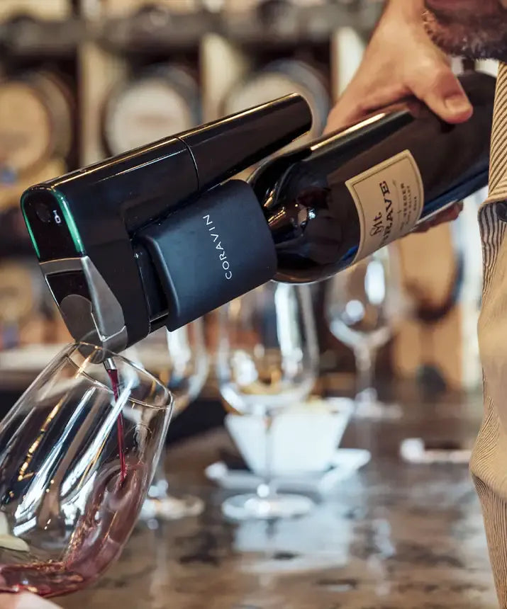 A person pouring wine into a glass using the Coravin Timeless Eleven Wine Preservation System.