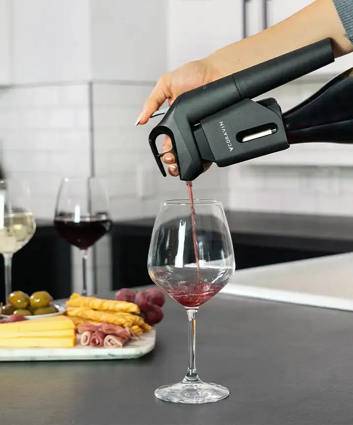 A person pouring wine into a glass using the Coravin Timeless Three+ Wine Preservation System.