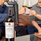 Coravin Timeless Three+ Wine Preservation System: A wine bottle with a gun on a table, people sitting on a couch, a person holding a glass of wine, and a close-up of a glass of wine.