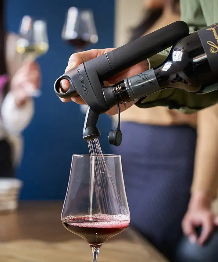 A person pouring wine into a glass using the Coravin Pivot™+ Wine Preservation System.