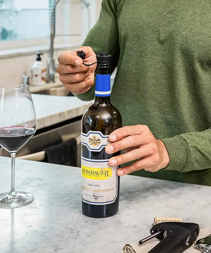 A person opening a bottle of wine with Coravin Pivot™ Stoppers 6 Pack.
