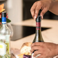 A person opening a bottle of wine with Coravin Screw Caps, compatible with most screw cap bottles.